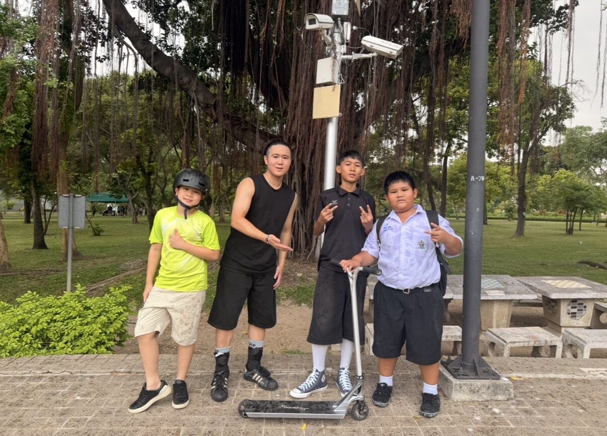 海外の公園で、現地の子どもたちとスクーターを囲んで記念撮影する様子