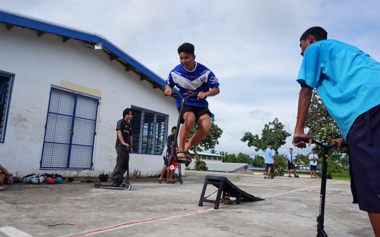 フィジーの学校で体育授業中、生徒がスクーターでランプをジャンプする様子